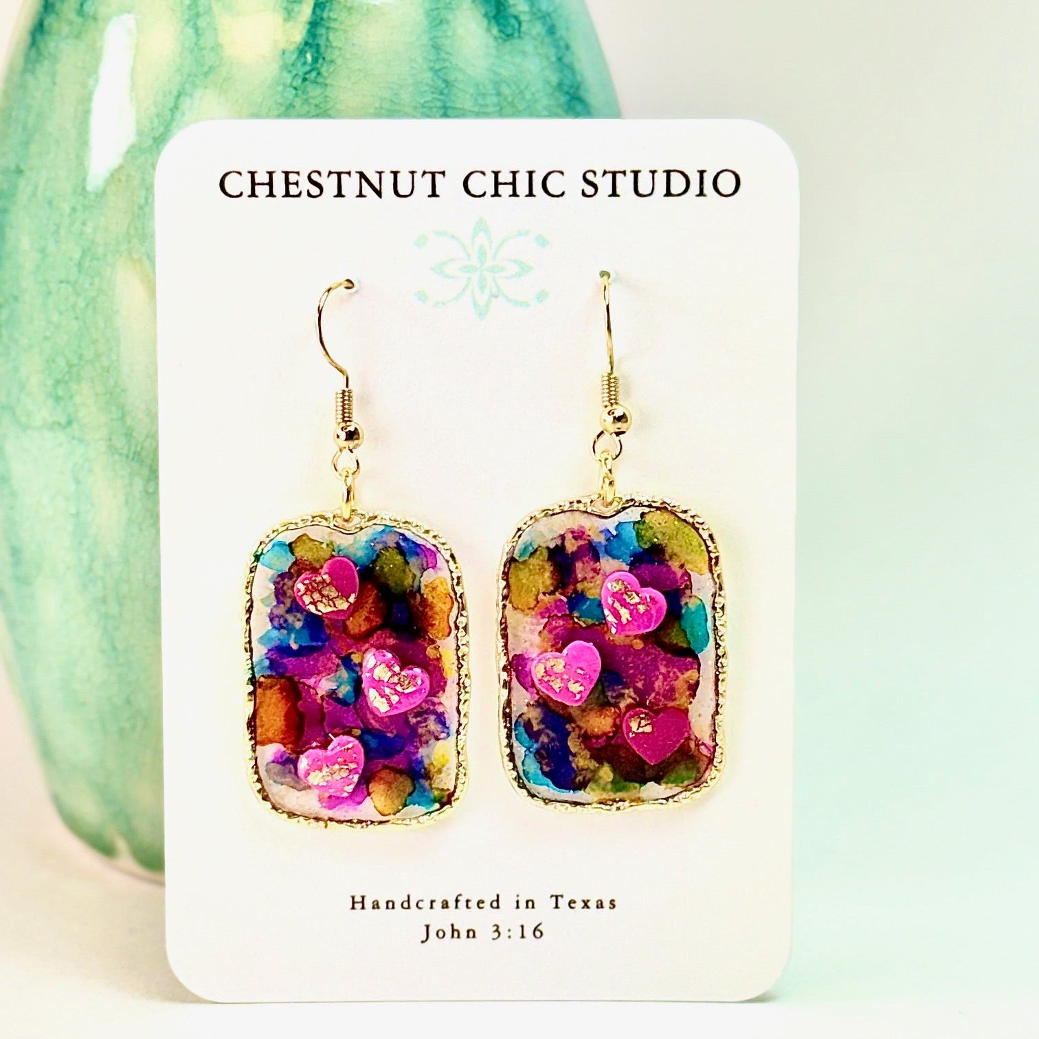 Multi colored 3D heart earrings with resin and clay on white card.