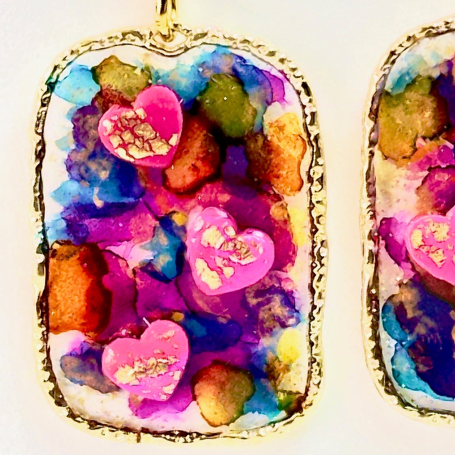 Multi colored 3D heart earrings with resin and clay on white card.