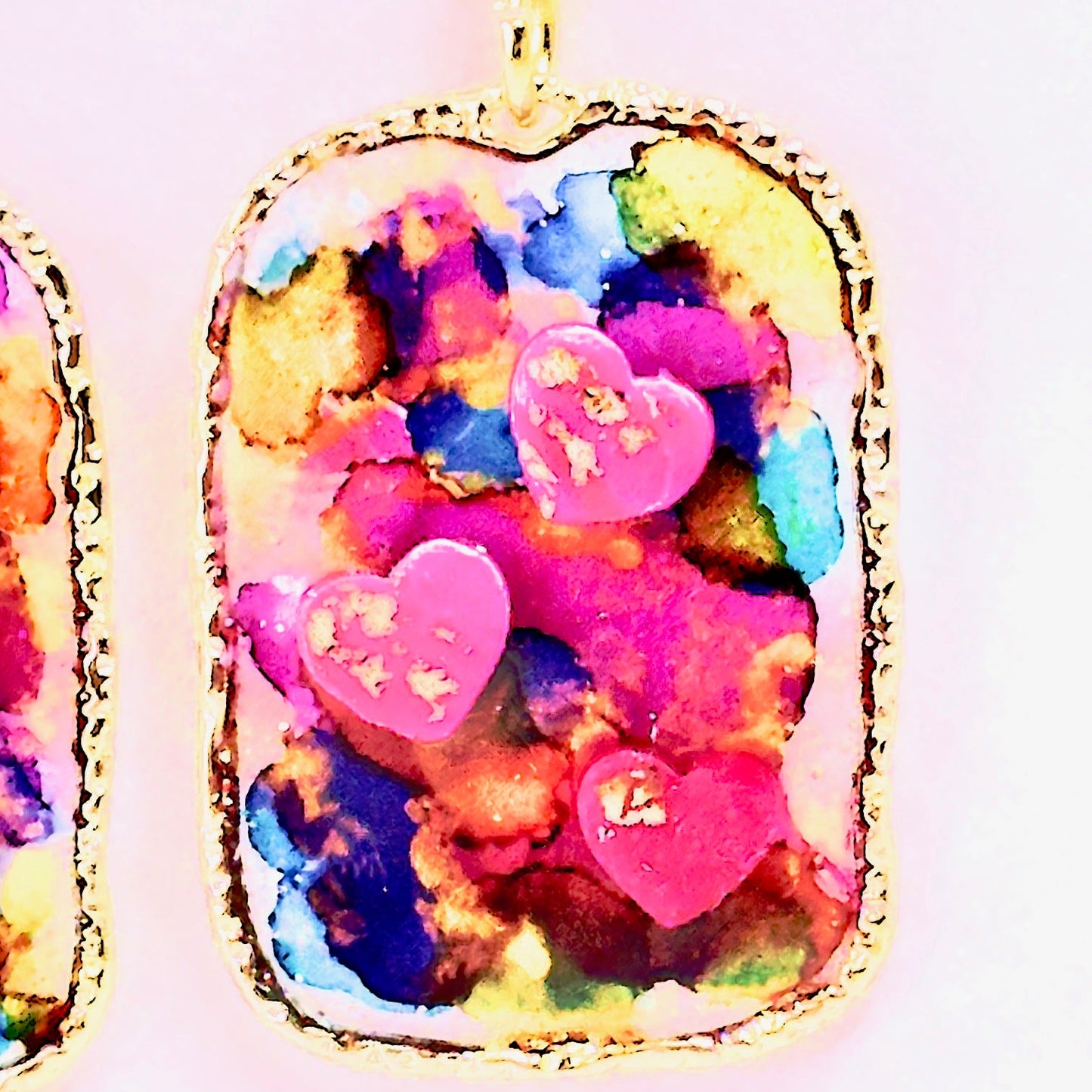Multi colored 3D heart earrings with resin and clay on white card.