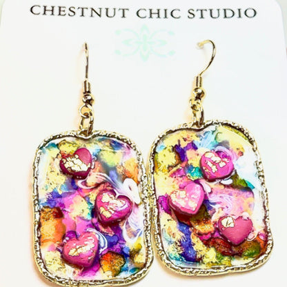 Multi colored 3D heart earrings with resin and clay on white card.