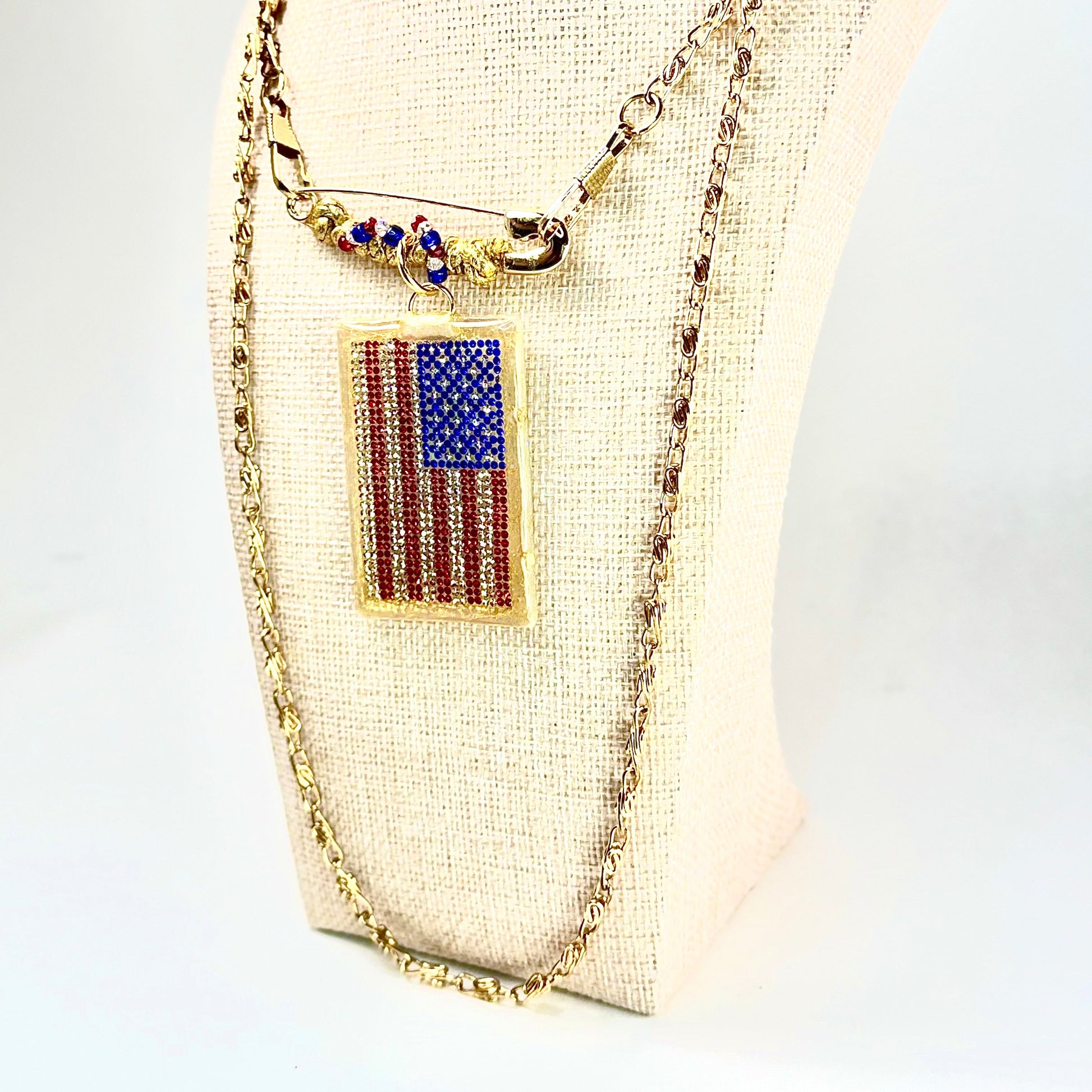 This one-of-a-kind, hand crafted artisan statement necklace is a convertible piece of jewelry that is a necklace, a brooch or pin, and a pendant. American flag is sparkling crystal with gold accents in leather, metal and vintage chain. Made in Conroe Texas by Chestnut Chic Studio. 