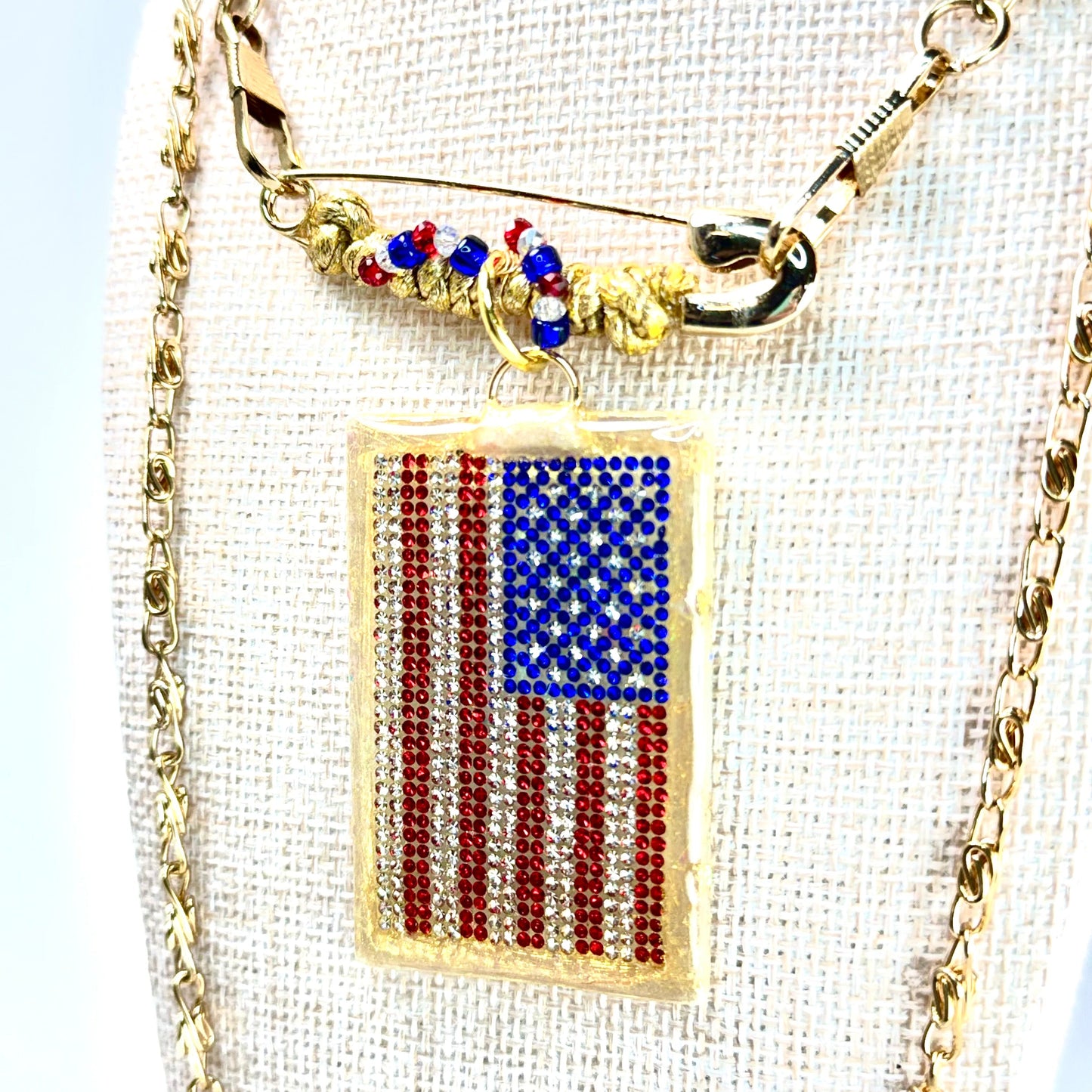 This one-of-a-kind, hand crafted artisan statement necklace is a convertible piece of jewelry that is a necklace, a brooch or pin, and a pendant. American flag is sparkling crystal with gold accents in leather, metal and vintage chain. Made in Conroe Texas by Chestnut Chic Studio. 