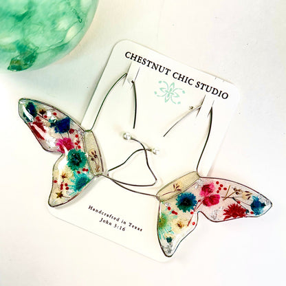 Hand crafted floating butterfly earrings with red, white and blue pressed flowers. Perfect for July 4th. Chestnut Chic Studio
