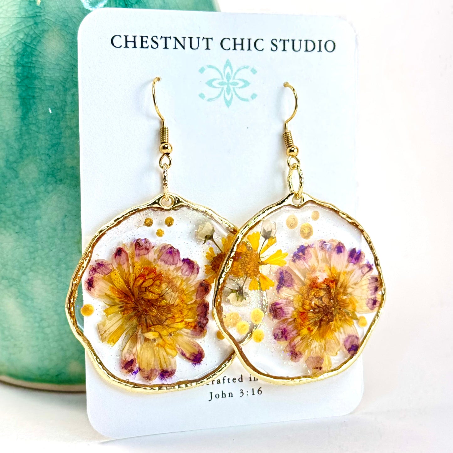 Hand pressed flower earrings with purple and yellow daisies set in a gold-tone hoop.