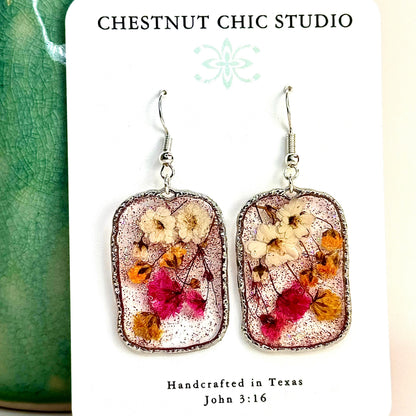 pressed flower earrings with mini buds in pink, yellow and white. Shimmering in a silver-tone setting. Make in Texas.